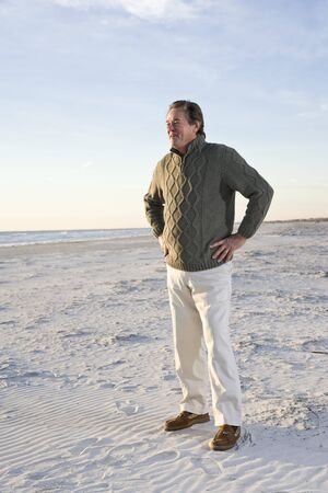 Senior man wearing sweater standing on beachの写真素材