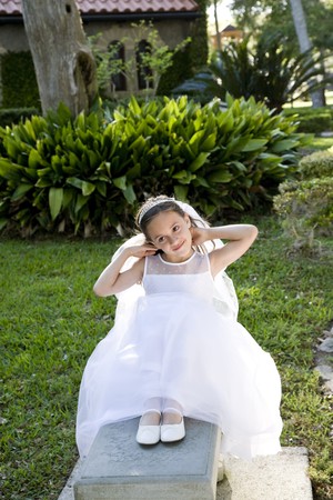 Beautiful 8 year old girl in white dress sitting on benchの写真素材