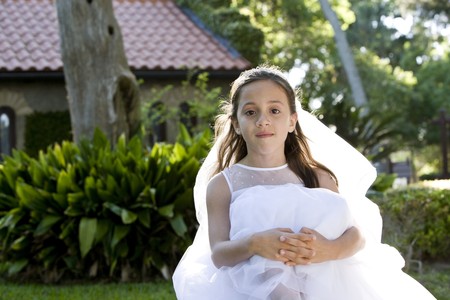 Beautiful 8 year old girl in white dress sitting on benchの写真素材