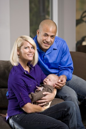 Happy parents cradling sleeping 3 month old baby at homeの写真素材
