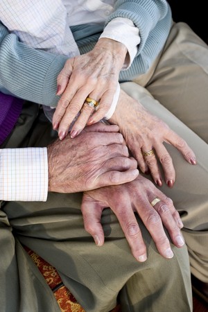 Close-up detail of hands of senior couple touching and resting on kneesの写真素材