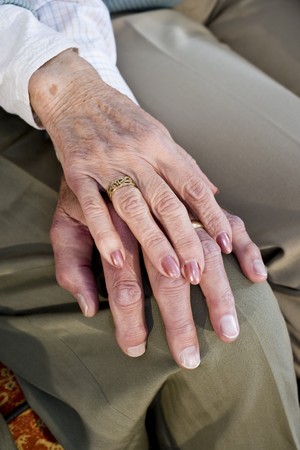 Close-up detail of hands of senior couple touching and resting on kneeの写真素材