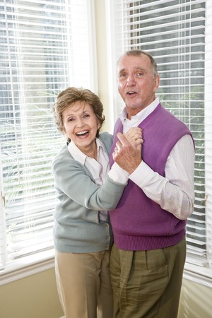 Happy senior couple dancing together in living roomの写真素材