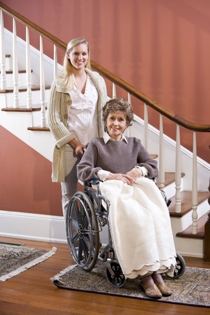 Elderly woman in 70s in wheelchair at home with nurseの写真素材