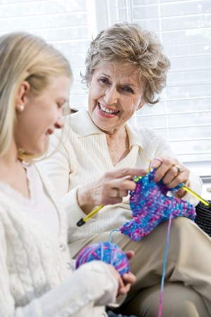 Grandmother knitting with granddaughter, focus on senior womanの写真素材