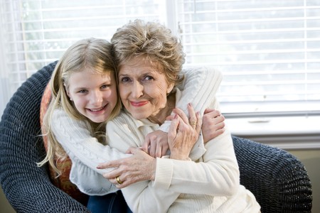 Portrait of happy young girl hugging grandmother at homeの写真素材