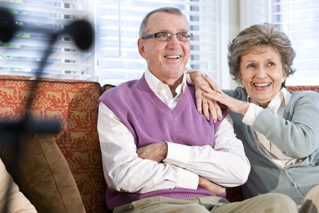 Happy senior couple sitting together on couch in living roomの写真素材