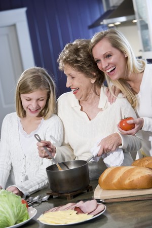 Grandmother with family cooking in kitchen, smiling and laughing togetherの写真素材