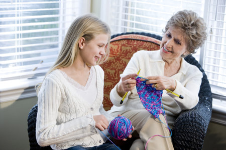 Grandmother teaching granddaughter how to knitの写真素材