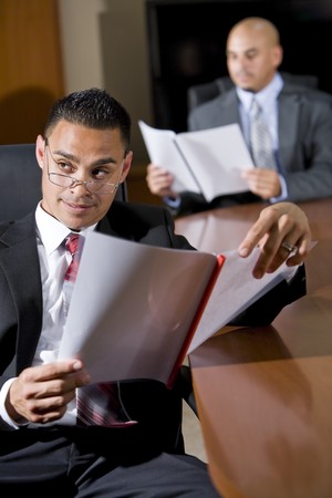 Hispanic businessmen in boardroom reviewing report, watching presentationの写真素材