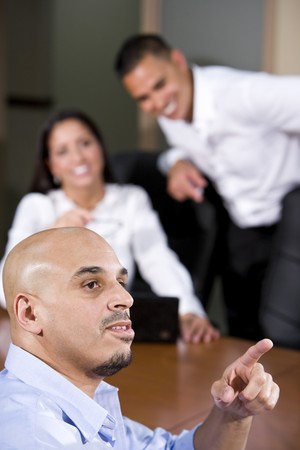 Hispanic business people in boardroom smiling watching presentation, focus on man in foregroundの写真素材
