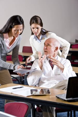 Scientist in lab coat talking to assistants in conference roomの写真素材