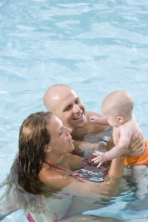 Parents with 6 month old baby playing in swimming poolの写真素材