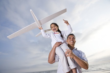 Hispanic dad and 9 year old child playing at beach with model planeの写真素材
