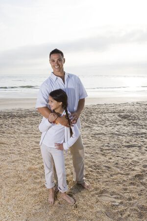Hispanic father and 9 year old daughter standing together on beachの写真素材