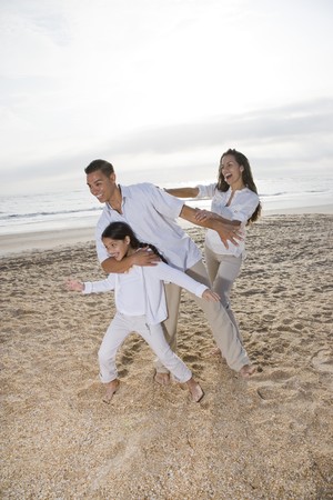 Hispanic family with 9 year old daughter having fun on beachの写真素材