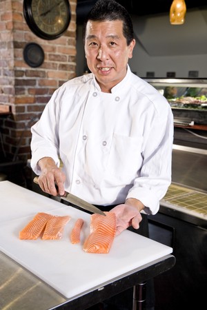 Japanese chef in restaurant slicing raw fish for salmon sushiの写真素材