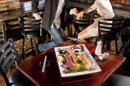 Platter of sushi on table in Japanese restaurant, couple at bar counter in backgroundの写真素材
