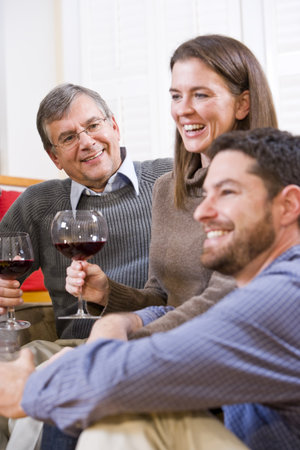 Mid-adult couple and senior parent drinking wine together