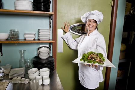 Chef working in restaurant standing at kitchen doorway with gourmet salad placeの写真素材