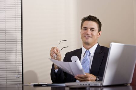 Businessman with laptop working in boardroom reading reportの写真素材