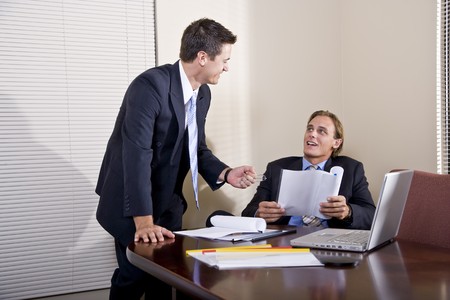 Business meeting - two businessmen in suits working together in boardroomの写真素材