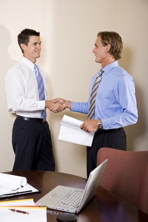Two businessmen meeting in office shaking handsの写真素材