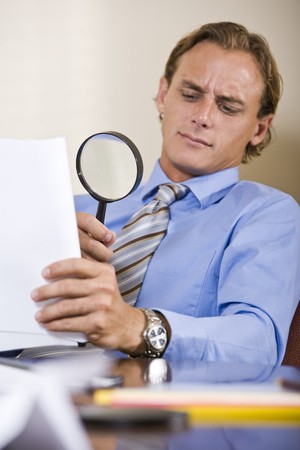 Businessman reading fine print in contract with magnifying glassの写真素材