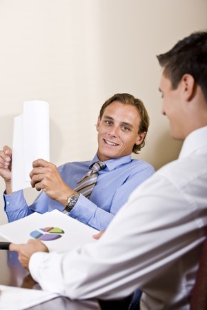 Businessmen discussing financial results looking at pie chartの写真素材