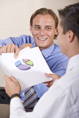 Businessmen discussing financial results looking at pie chartの写真素材