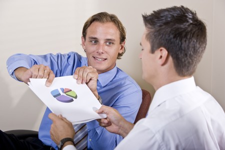 Businessmen discussing financial results looking at pie chartの写真素材