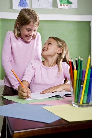 Back to school - 8 year old girls writing in notebook in classroomの写真素材