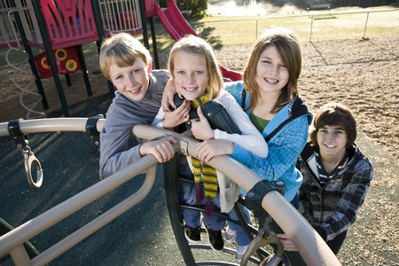 Group of children (10 to 15 years) standing together on playground equipmentの写真素材