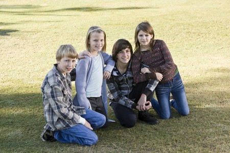 Four children (10 to 15 years) posing together on grassの写真素材