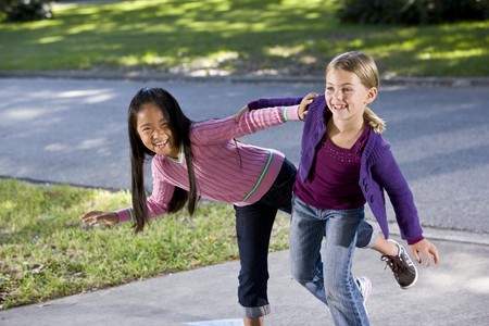 Two happy friends playing  on driveway - girls 7 yearsの写真素材