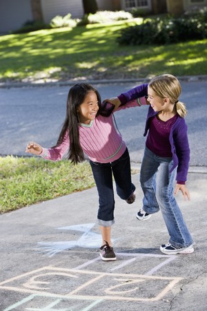Multiracial friends having fun playing hopscotch on drivewayの写真素材
