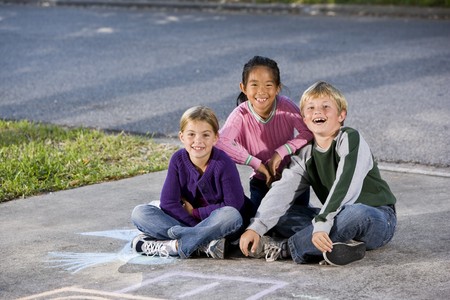 Portrait of multi-ethnic kids sitting together.  Girls 7 year, boy 9.の写真素材