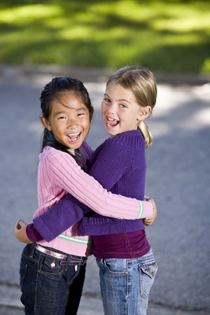 Two girls, 7 years, hugging and laughingの写真素材