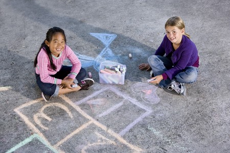Two girls, 7 years, drawing pictures on driveway with chalkの写真素材