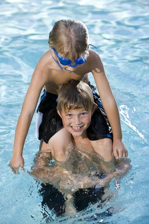 Boys, 7 and 9 years, playing in swimming pool, sitting on shouldersの写真素材