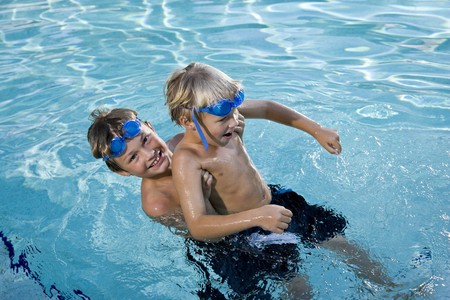 Boys will be boys - playing on side of swimming pool, 7 and 9 yearsの写真素材