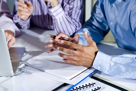 Three office workers working together on project, gesturing, focus on hand in middleの写真素材