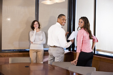 Three multiethnic office workers reading report in boardroom, focus on couple on rightの写真素材