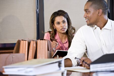 African American businessman and Indian businesswoman working together in office, focus on womanの写真素材