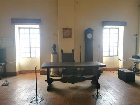 A view of the interior of an old school building with a wooden table and a clockの写真素材