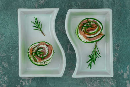 smoked salmon with cucumber and soft cheese rolls on white plateの写真素材