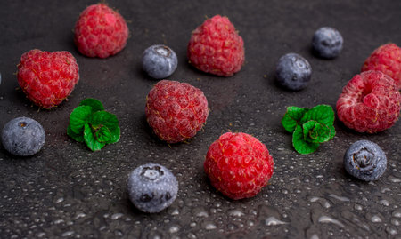 fresh raspberry blueberry with mint on black backgroundの写真素材
