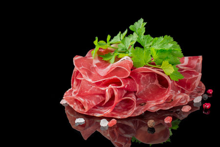 Parma ham ,prosciutto and salami slices on black backgroundの写真素材