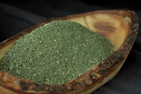 Powdered oregano in wooden bowl on black backgroundの写真素材