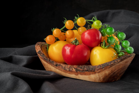red cherry  tomatoes  on wooden spoon dark backgroundの写真素材